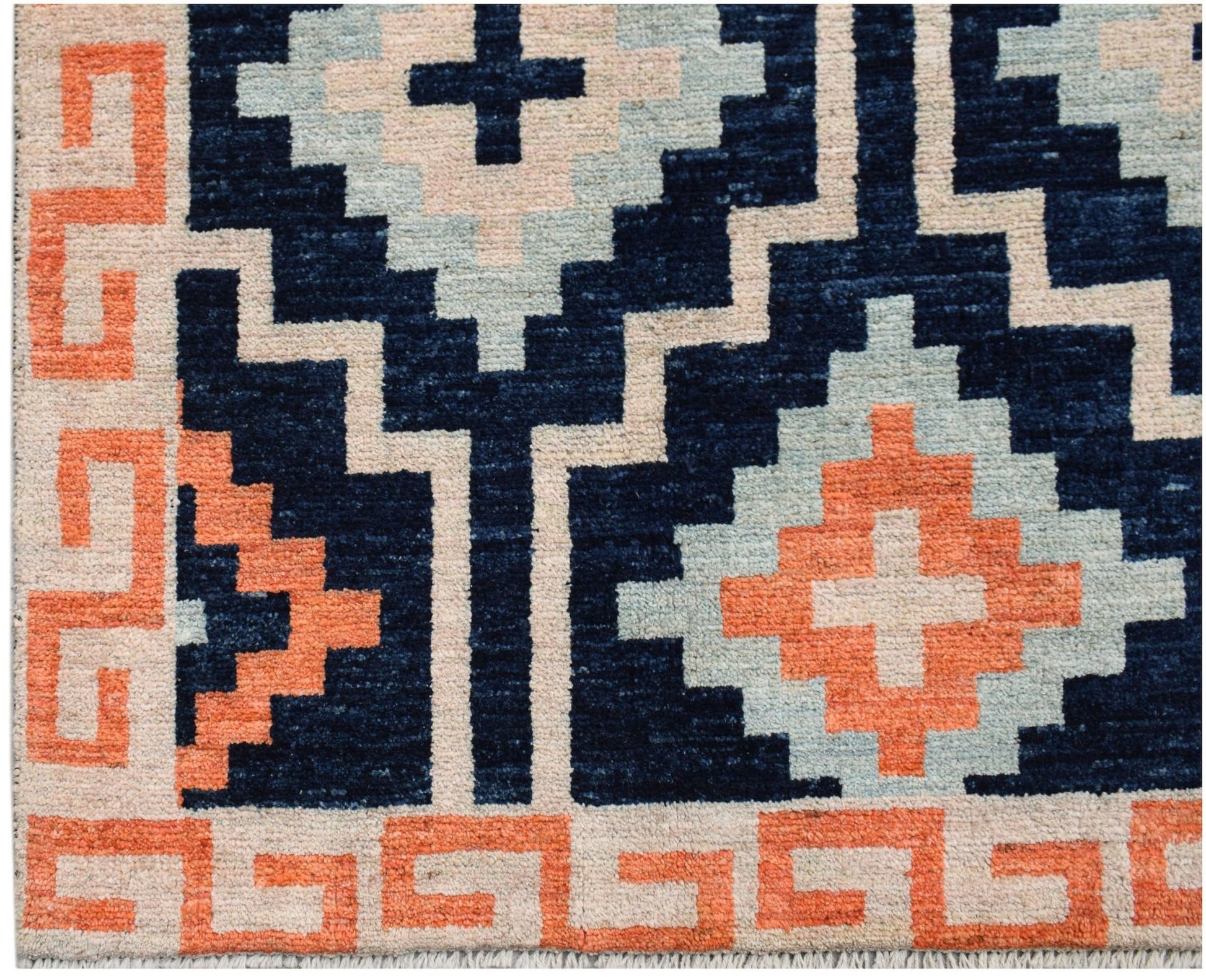 A hand-knotted wool rug featuring a geometric pattern in navy, light blue, and orange.