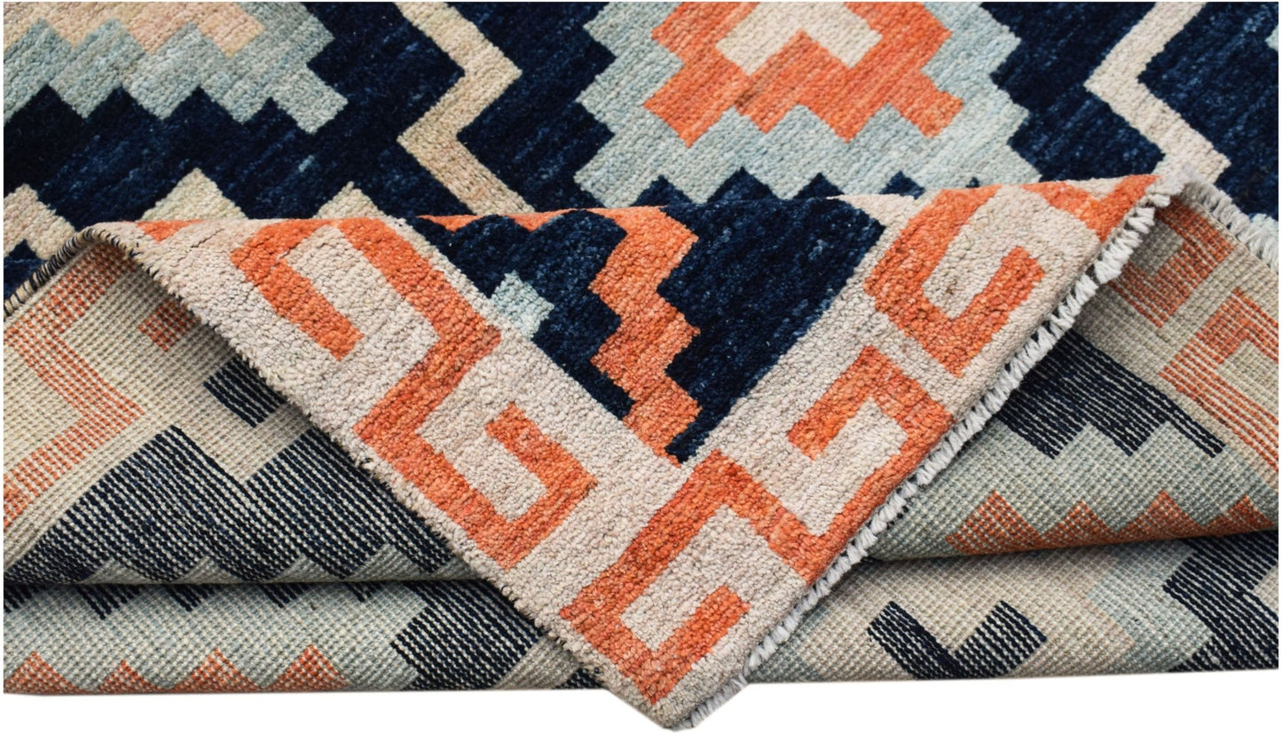 A hand-knotted wool rug featuring a geometric pattern in navy, orange, and light blue.