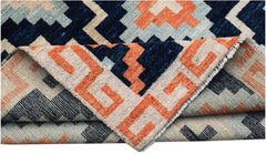 A hand-knotted wool rug featuring a geometric pattern in navy, orange, and light blue.