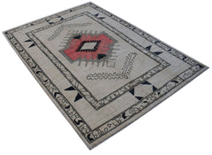 A handmade wool rug from Afghanistan featuring a central geometric medallion on a beige field.