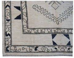 A handmade Afghan wool rug featuring a cream background with black geometric tribal patterns.