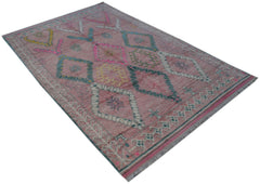 A handmade pink wool rug from Afghanistan featuring a geometric diamond pattern and fringe edges.