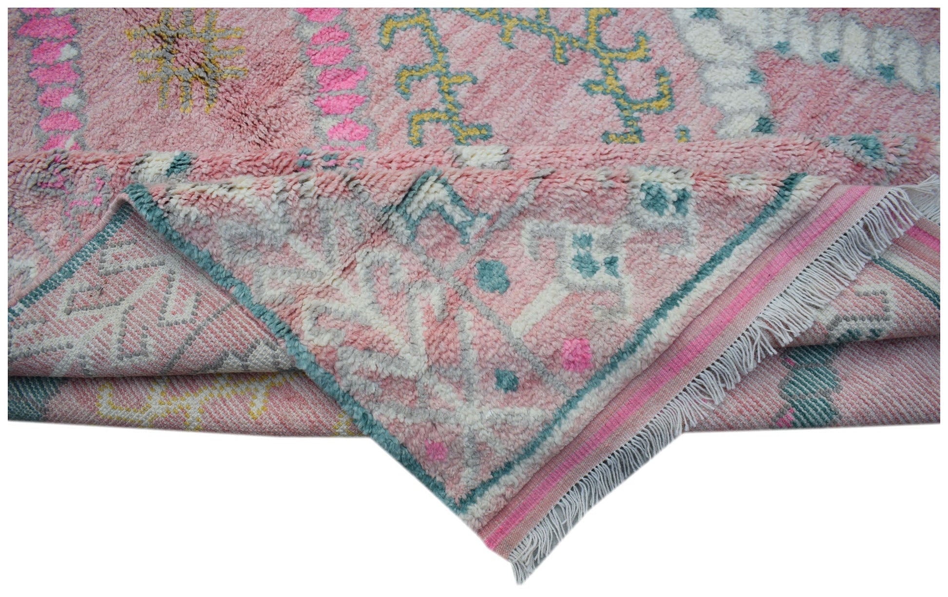 A handmade transitional wool rug in pink with colorful tribal patterns and fringed edges.