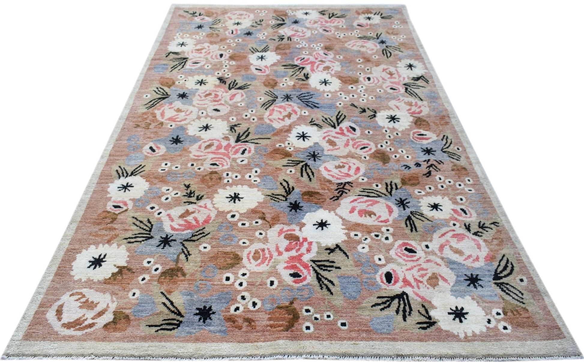 A hand-knotted wool rug featuring a floral pattern in pink, blue, and white on a tan background.