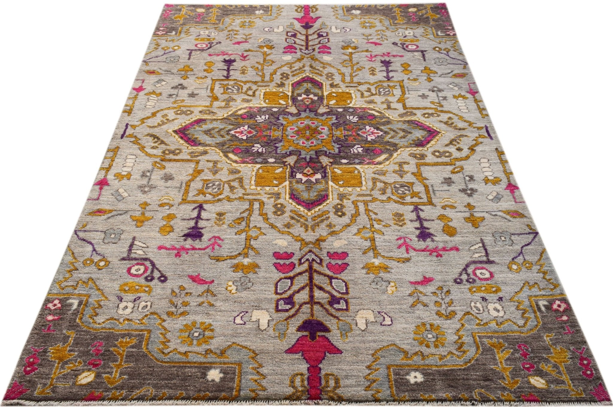 A hand-knotted wool rug featuring a grey background with a vibrant geometric floral pattern.