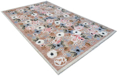A handknotted wool rug featuring a floral pattern in shades of pink, blue, and white on a tan base.