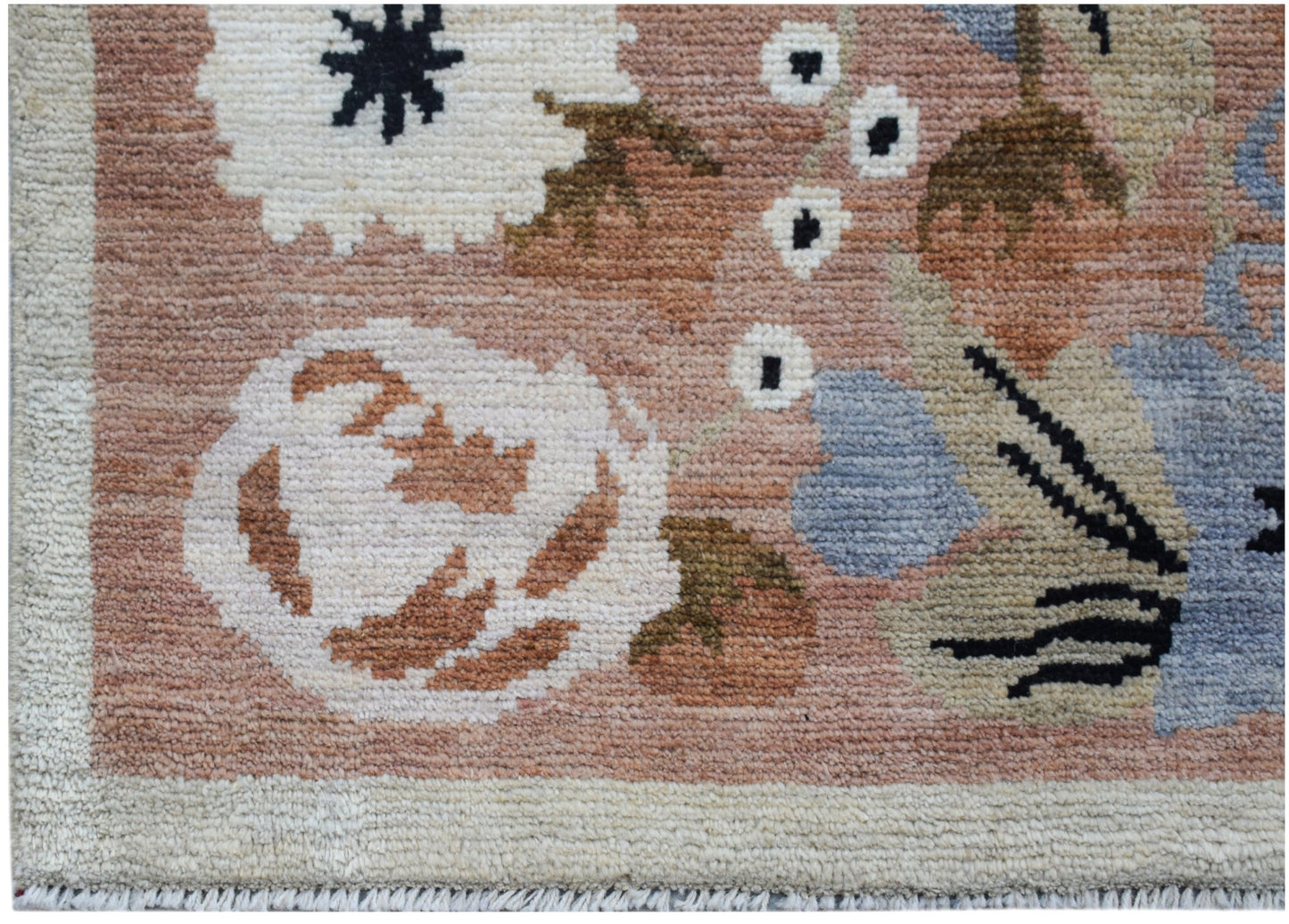 A handknotted wool rug featuring a floral pattern in shades of pink, blue, and cream.