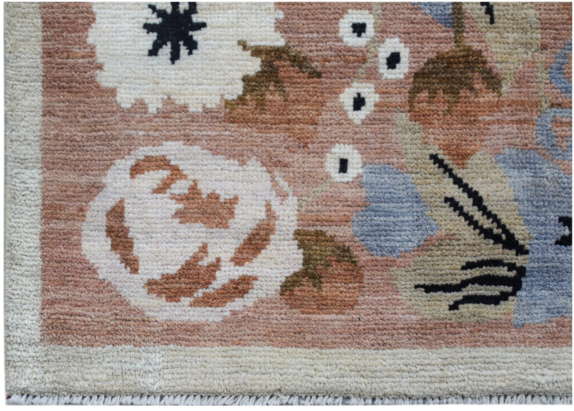 A handknotted wool rug featuring a floral pattern in shades of pink, blue, and cream.