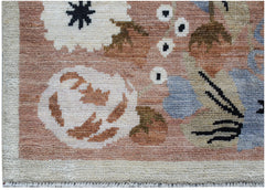 A handknotted wool rug featuring a floral pattern in shades of pink, blue, and cream.