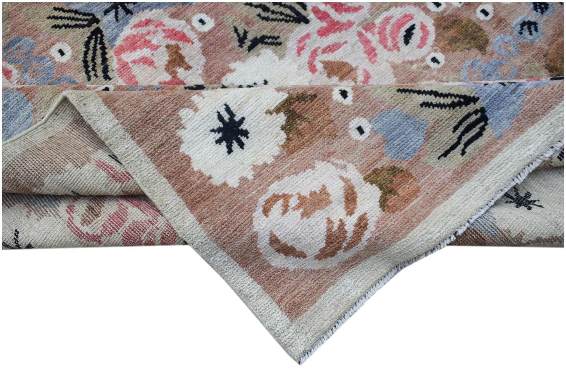 A handknotted wool rug featuring a floral pattern in shades of pink, blue, and cream.