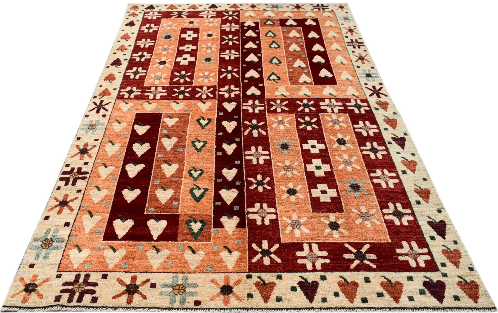 A handknotted wool rug featuring a geometric pattern of hearts and flowers in red and orange tones.
