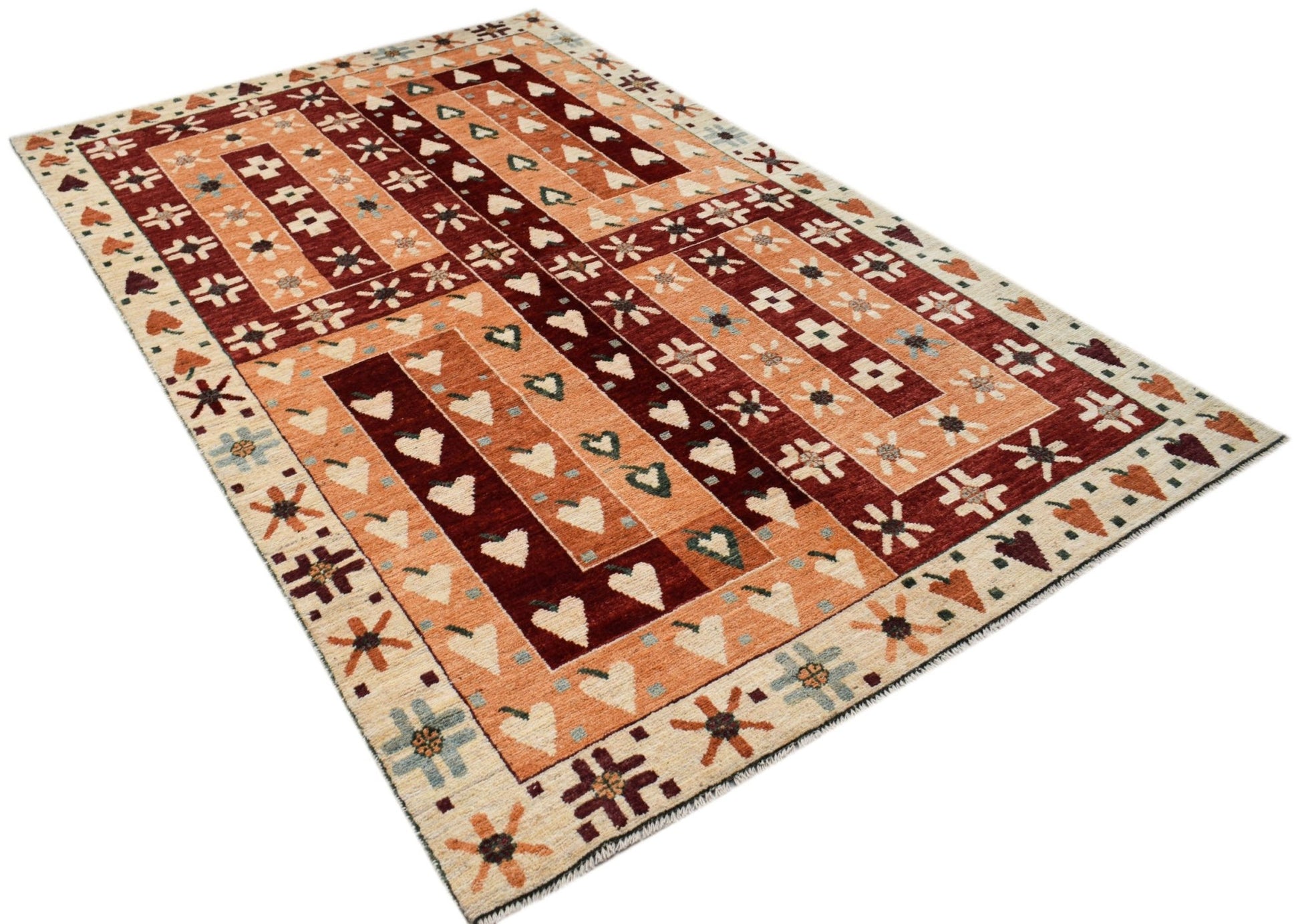 A hand-knotted wool rug featuring a geometric pattern of hearts and stars in rust and cream tones.