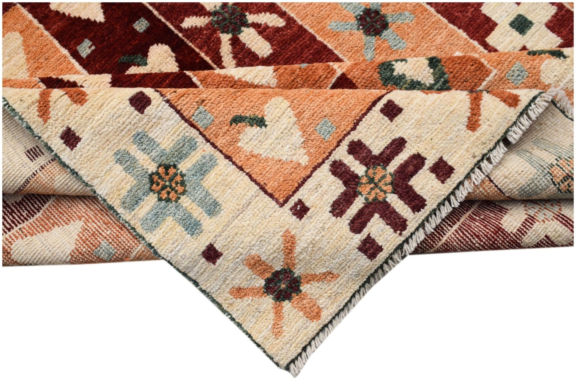 A hand-knotted wool rug featuring geometric floral patterns in shades of red, orange, and cream.