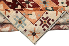 A hand-knotted wool rug featuring geometric floral patterns in shades of red, orange, and cream.