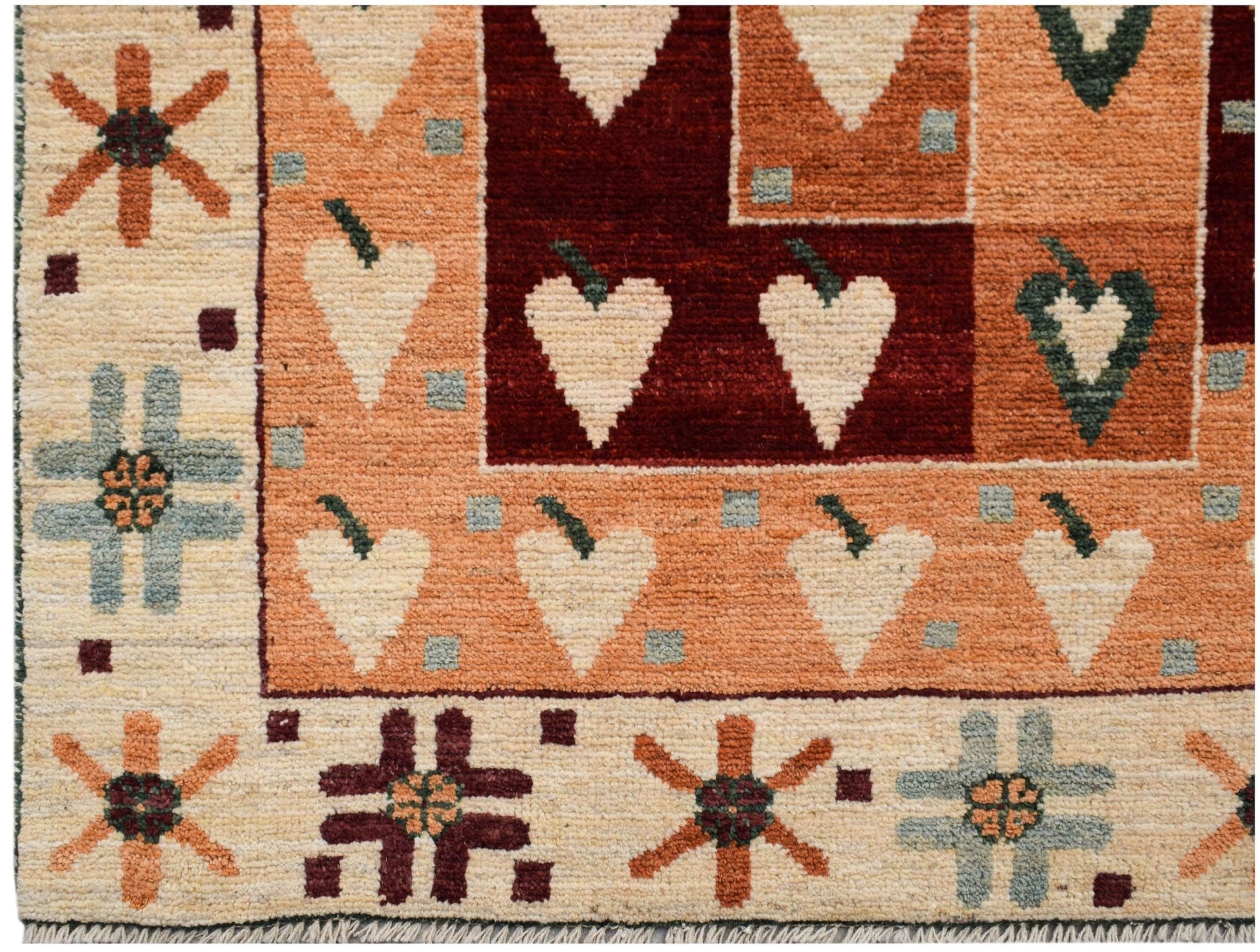 A hand-knotted wool rug featuring geometric heart motifs and floral patterns in earthy tones.