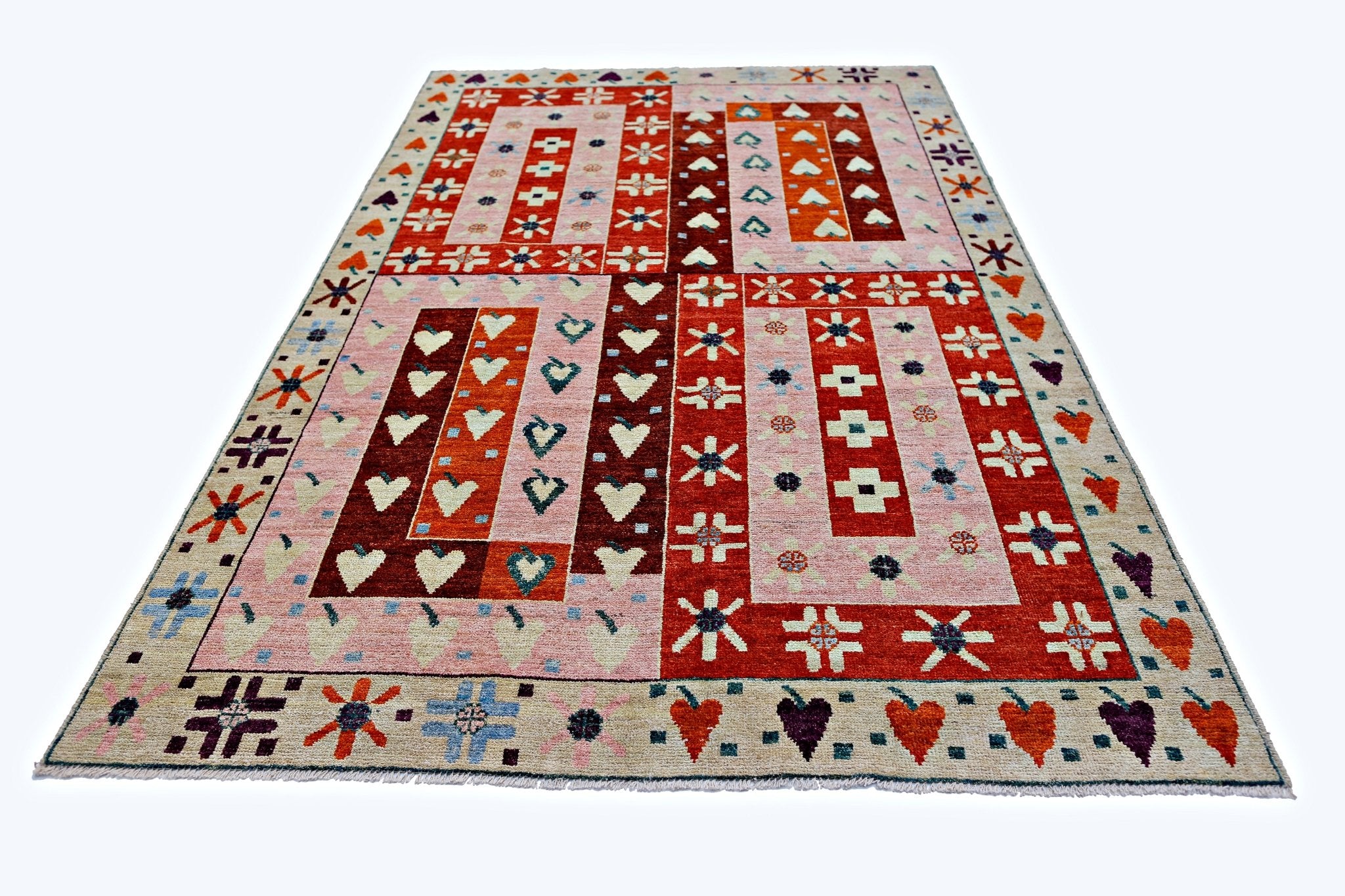 A handmade wool rug from Afghanistan featuring a geometric pattern of hearts and stars in red and pink.