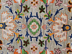 A handmade transitional Kohi rug featuring a detailed floral pattern in muted earth tones.