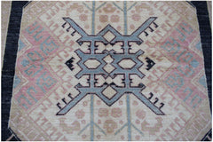 A handmade Afghan wool rug featuring a central blue geometric medallion on a cream background.