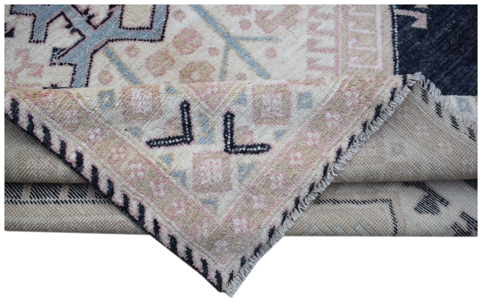 A corner of a handmade wool rug with a geometric pattern in blue, pink, and cream tones.