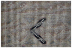 A close-up of a handmade wool rug featuring a beige background with a dark chevron pattern.