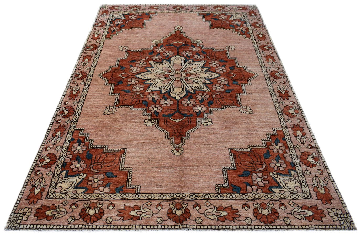 Handmade Afghan Kohi wool rug featuring a central floral medallion on a dusty pink background.