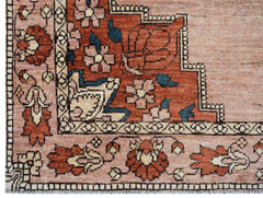 A close-up of an Afghan Kohi rug featuring a geometric floral pattern in rust, pink, and blue.