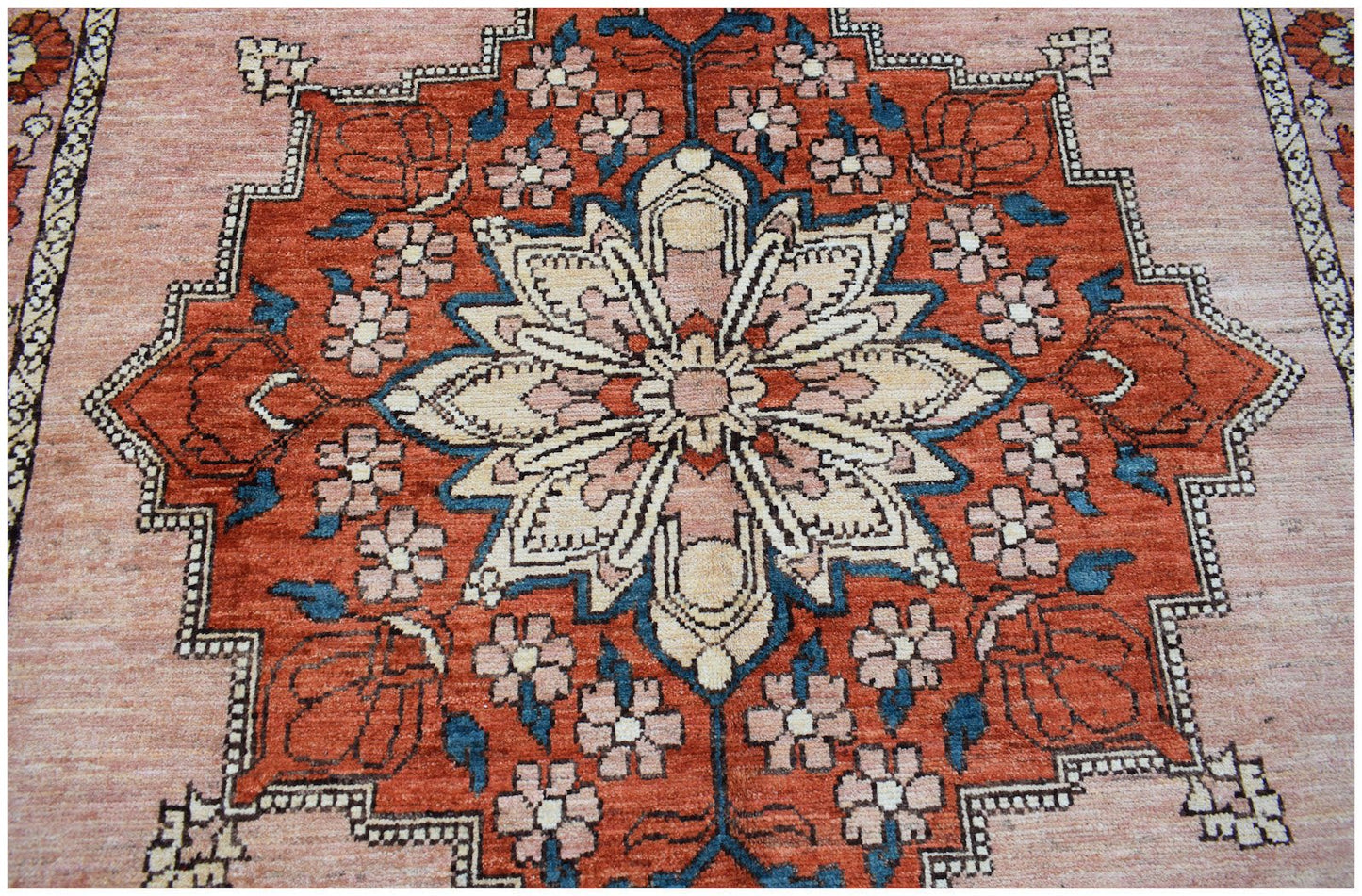 Handmade Afghan Kohi wool rug featuring a central floral medallion in rust, cream, and blue tones.