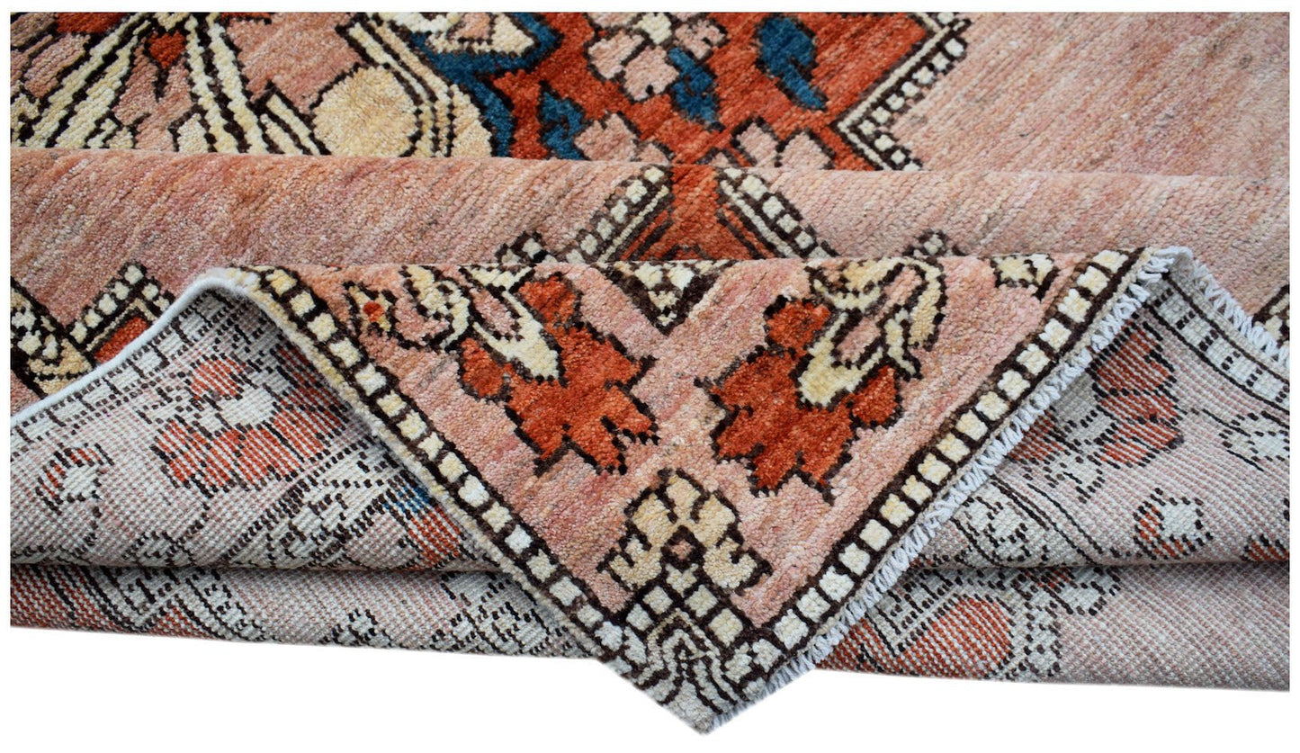 A folded Afghan Kohi rug featuring a geometric tribal pattern in shades of orange, blue, and cream.