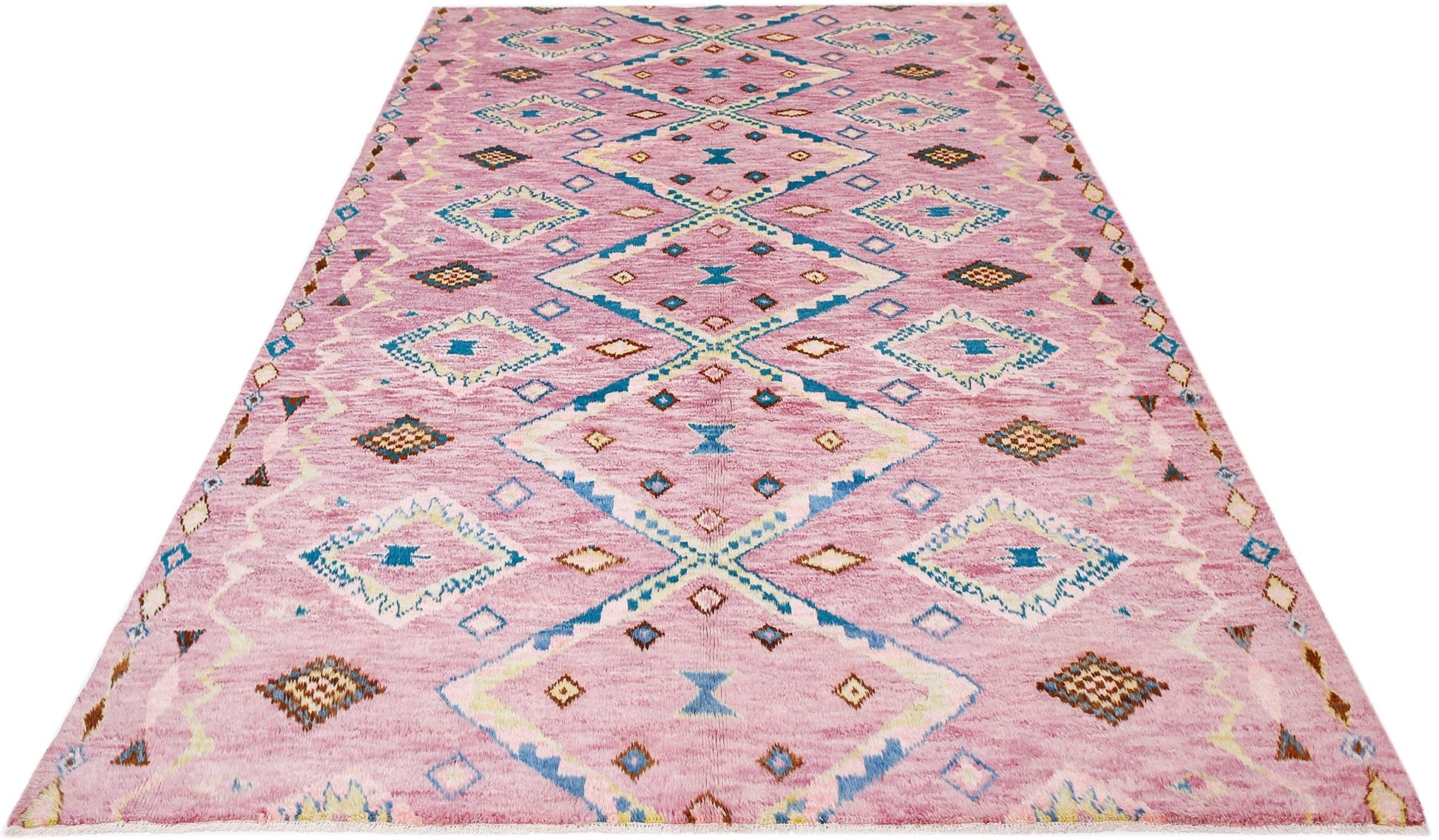 A handmade Afghan wool rug featuring a pink field with a repeating blue and cream diamond pattern.