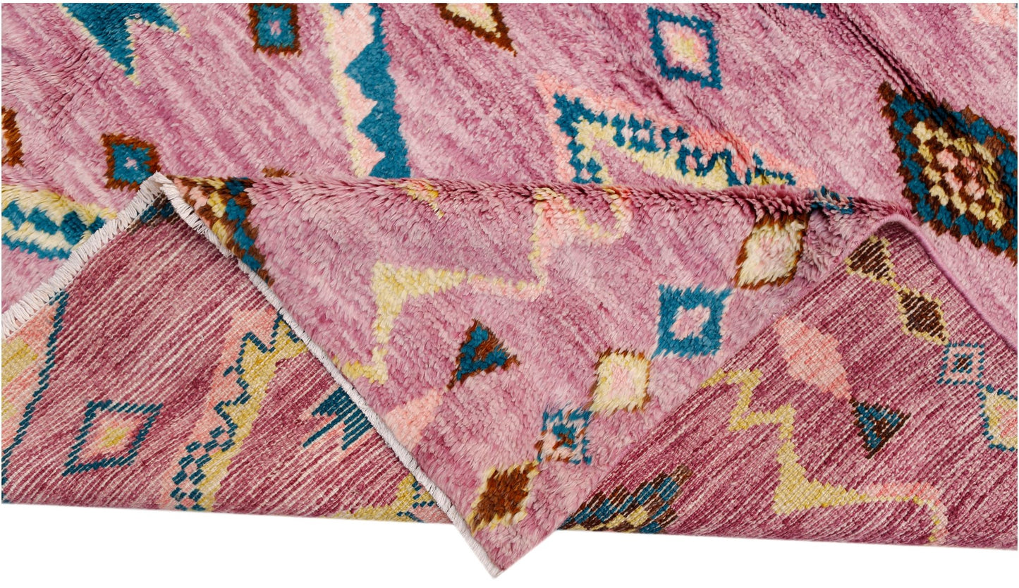 A handmade wool rug in shades of pink featuring a geometric pattern in blue, yellow, and brown.