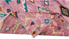 A handmade wool rug in shades of pink featuring a geometric pattern in blue, yellow, and brown.