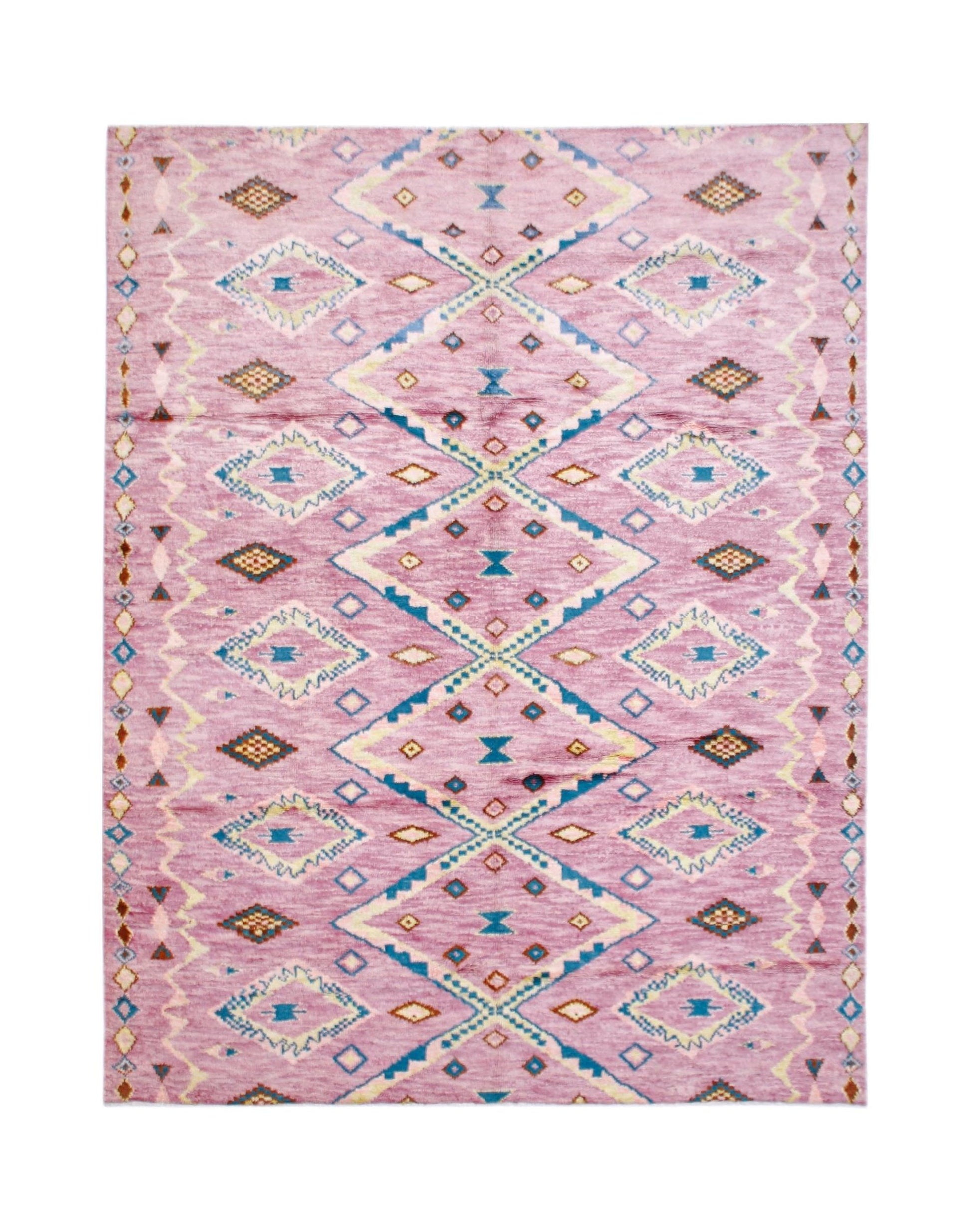 A handmade wool rug featuring a pink background with a repeating blue and cream diamond pattern.