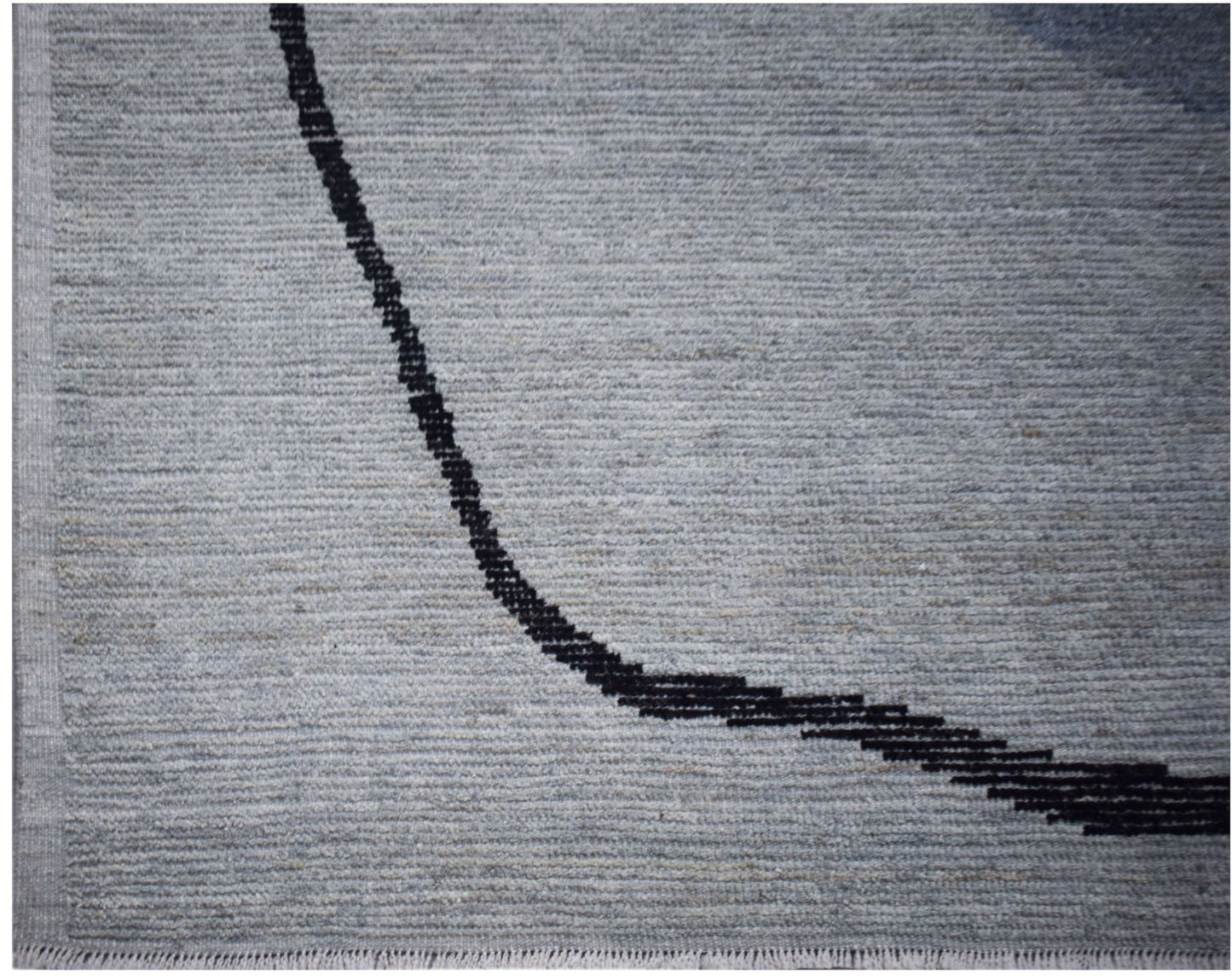 A hand-knotted Afghan rug in grey wool featuring a minimalist black curved line design.