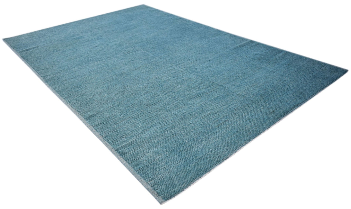 A rectangular hand-knotted Afghan rug in a solid, textured blue wool with a low pile.