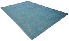A rectangular hand-knotted Afghan rug in a solid, textured blue wool with a low pile.