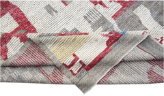 A hand-knotted Afghan wool rug featuring a geometric pattern in red, grey, and cream tones.