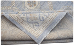 A folded transitional Oushak rug featuring a light blue and beige geometric pattern.