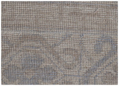 A close-up of a handmade wool rug featuring a soft, neutral palette and a subtle, faded pattern.