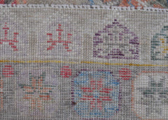 A close-up view of a handwoven wool rug featuring geometric patterns in muted, earthy tones.