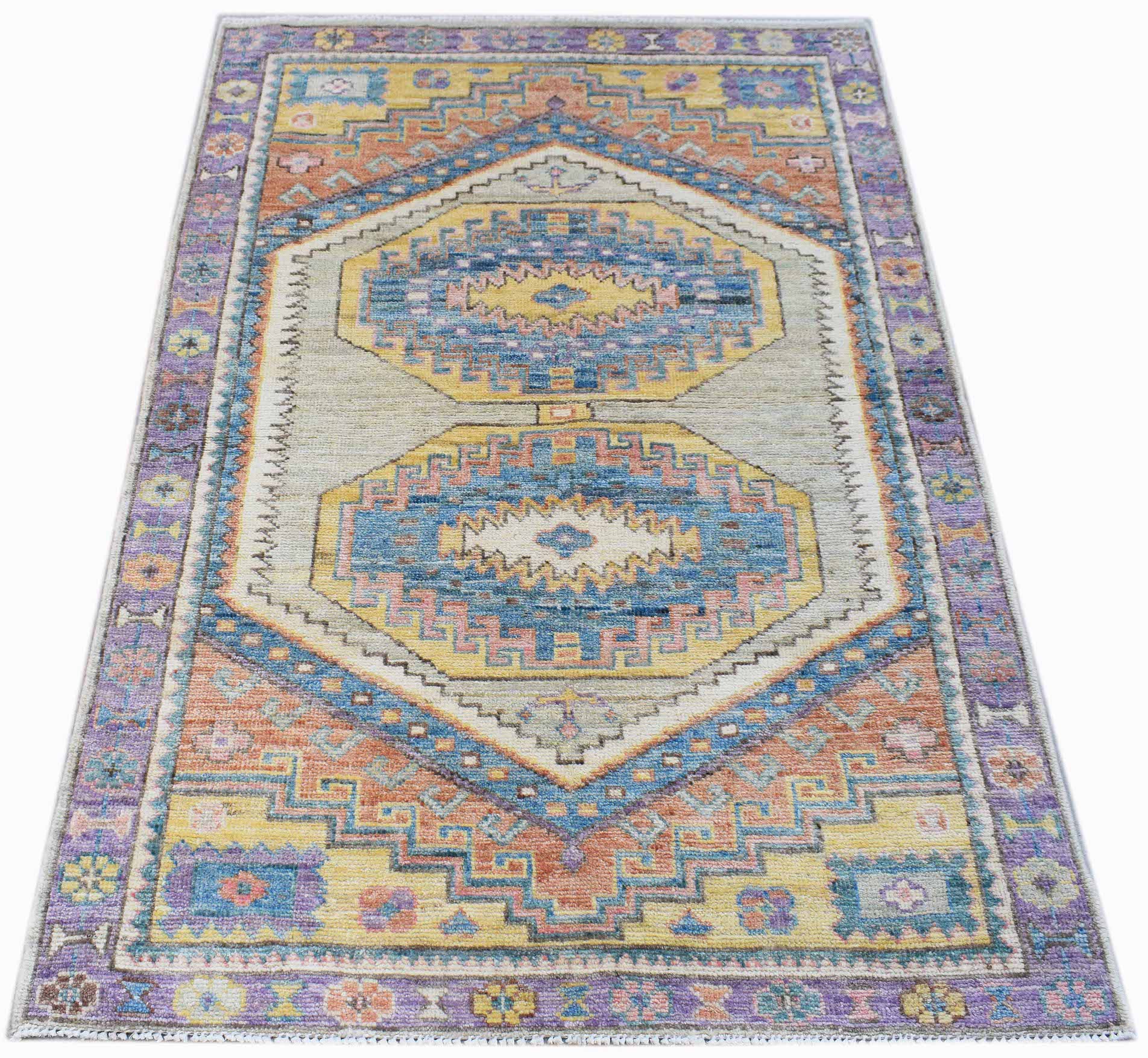 A handwoven transitional Oushak rug featuring a geometric pattern in blue, yellow, and orange.