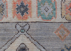 A handwoven transitional Oushak rug featuring geometric patterns in muted tones on wool.