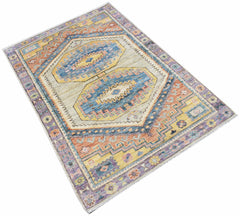A handwoven transitional Oushak rug featuring a geometric pattern in blue, yellow, and orange.