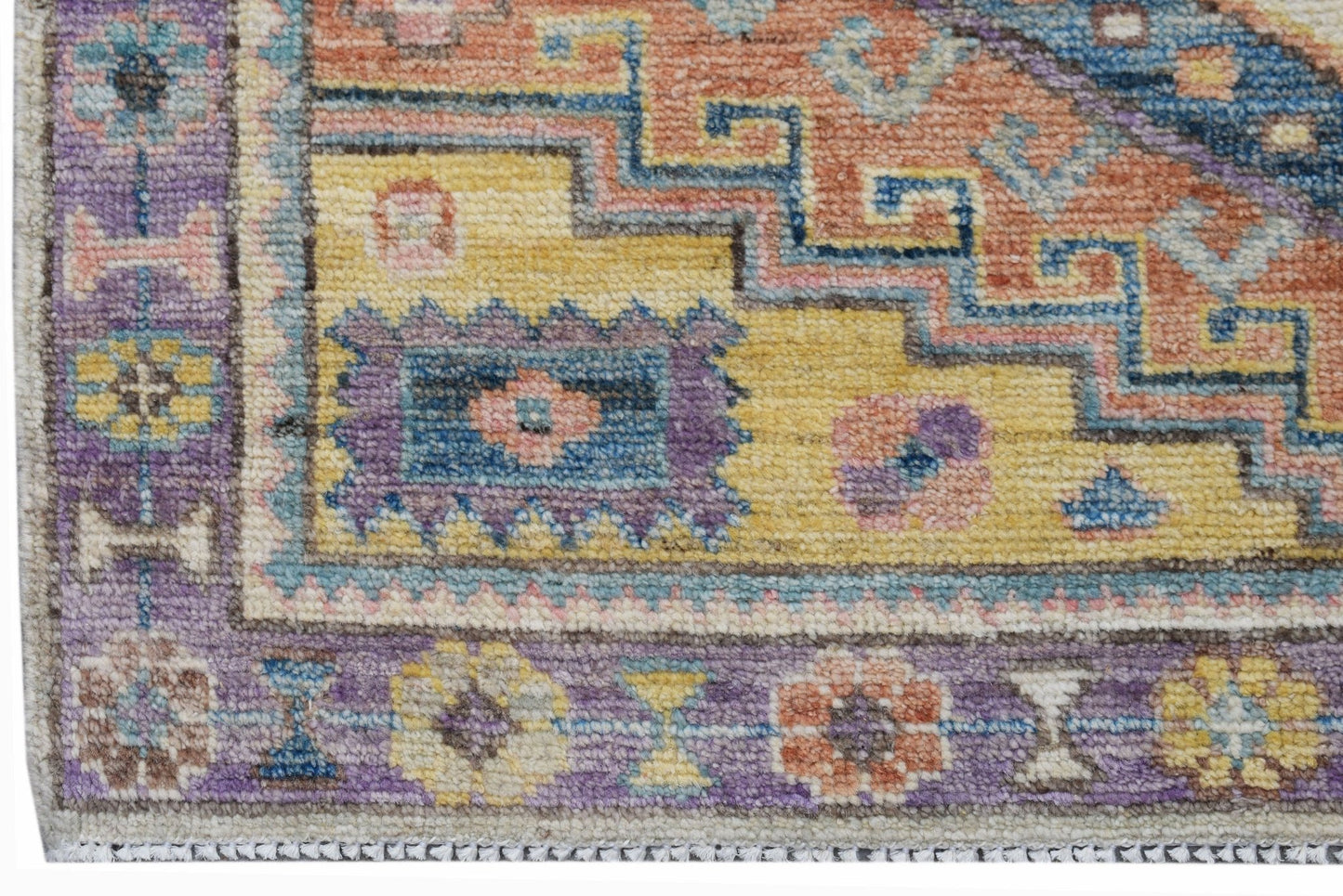 A handwoven transitional Oushak rug featuring a geometric floral pattern in vibrant colors.
