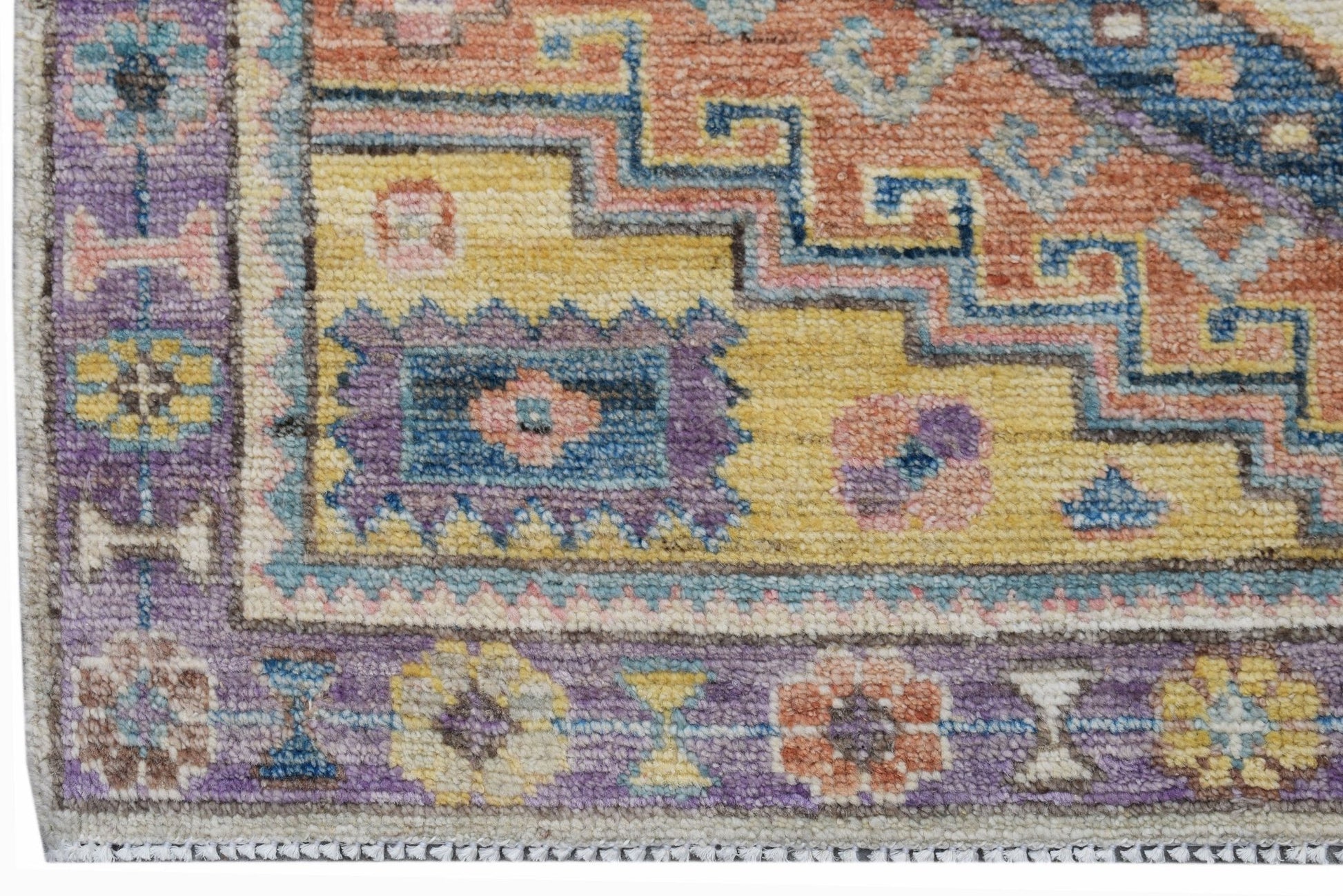 A handwoven transitional Oushak rug featuring a geometric floral pattern in vibrant colors.