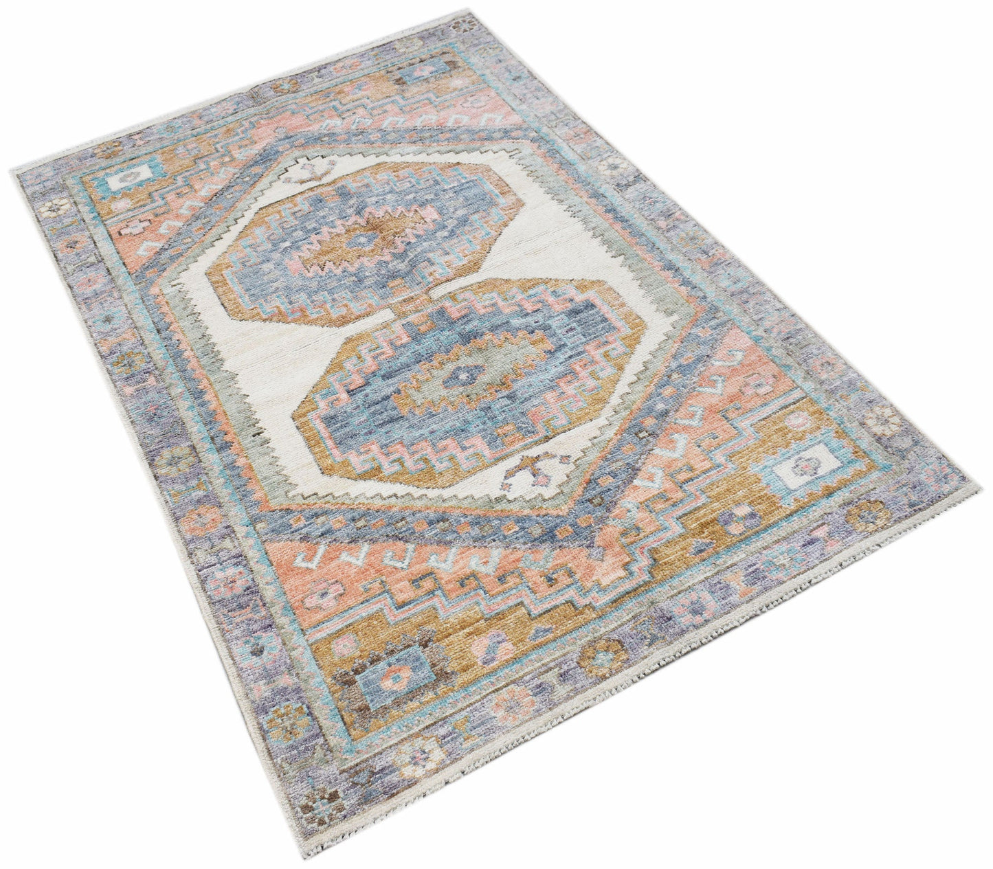 A handwoven transitional Oushak rug featuring a geometric pattern in blue, pink, and tan tones.
