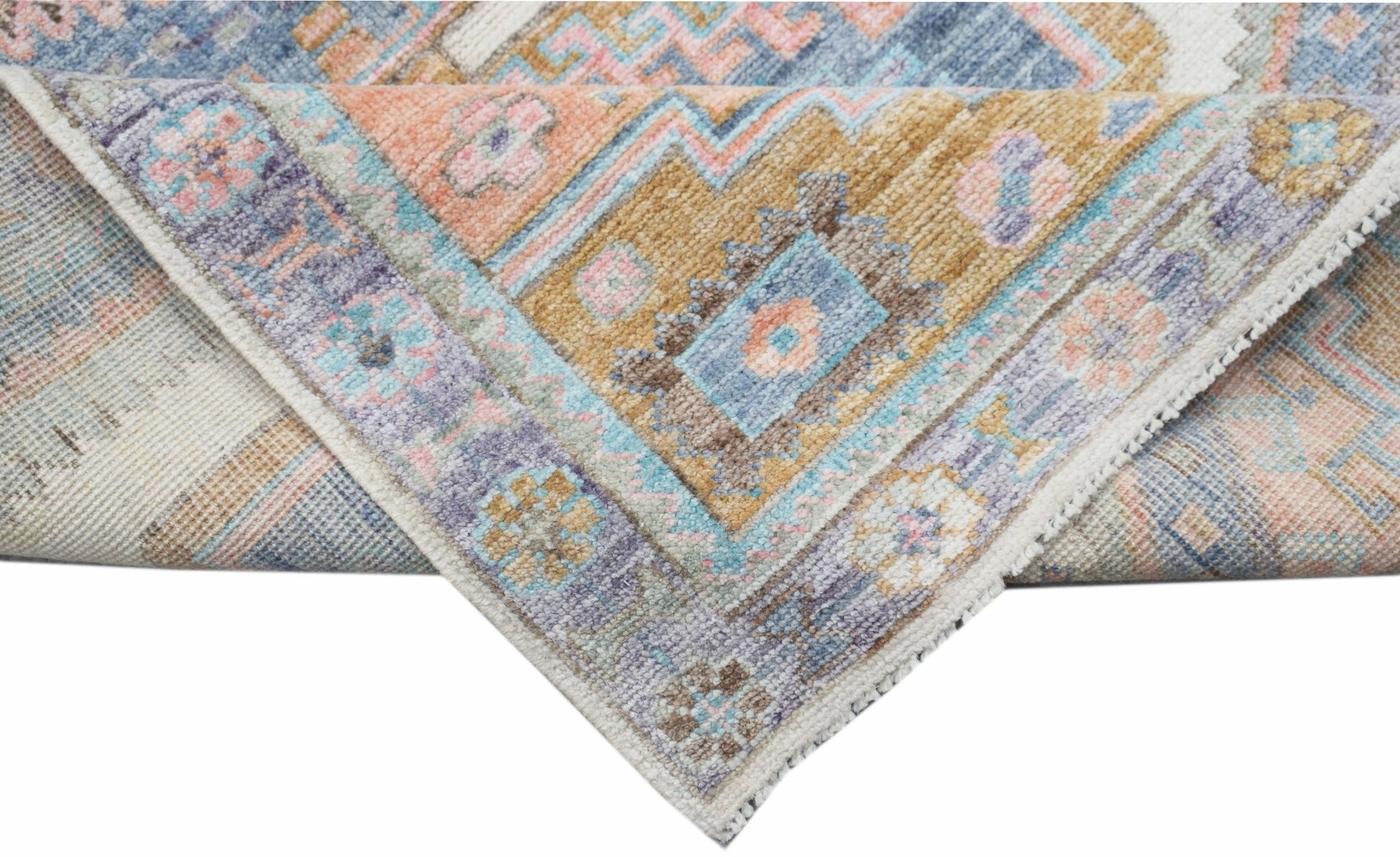 A handwoven transitional Oushak rug featuring a floral pattern in muted blue, pink, and gold tones.