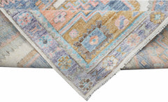 A handwoven transitional Oushak rug featuring a floral pattern in muted blue, pink, and gold tones.