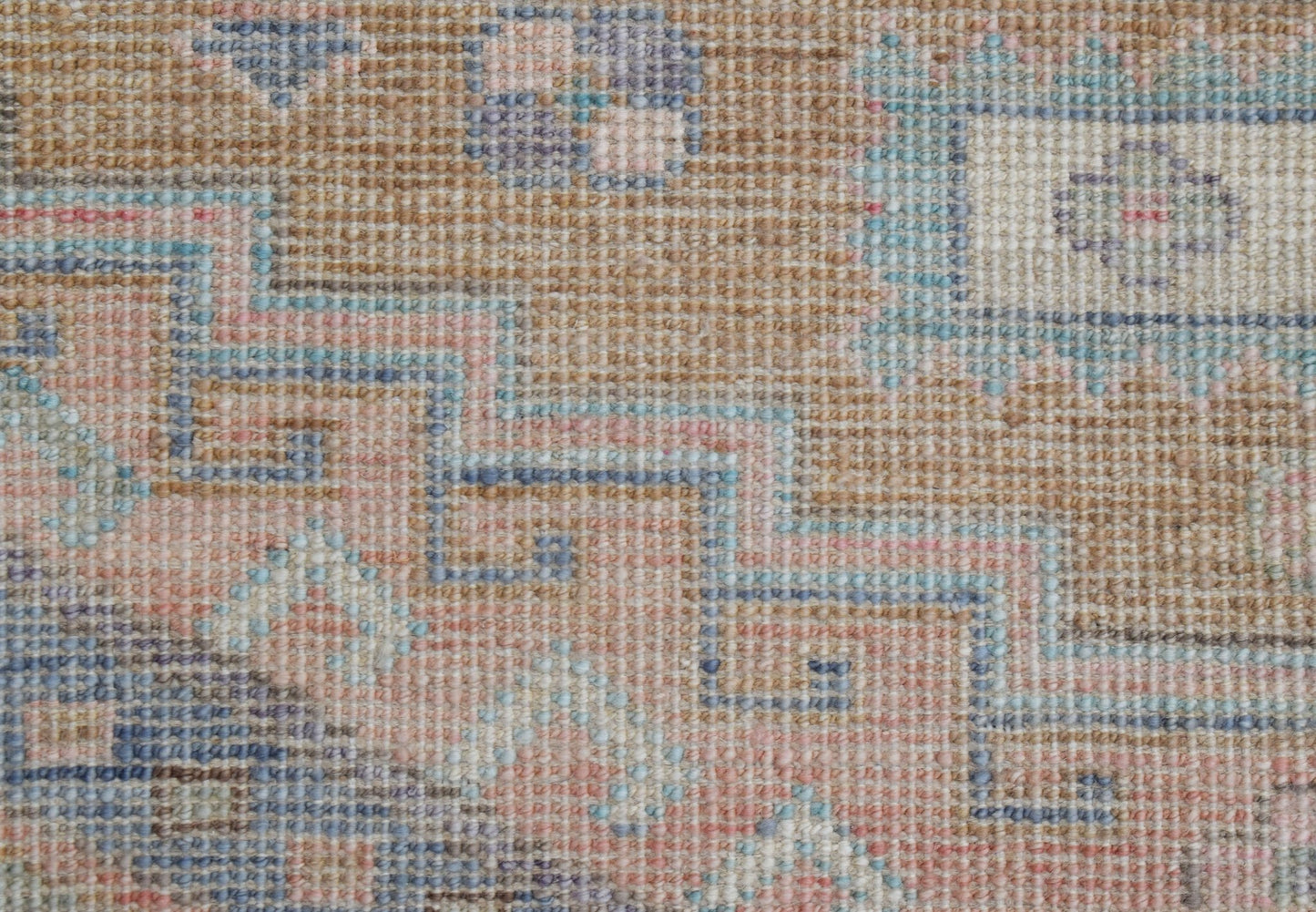A handwoven transitional Oushak rug featuring a geometric pattern in soft blue, pink, and tan tones.