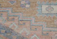 A handwoven transitional Oushak rug featuring a geometric pattern in soft blue, pink, and tan tones.