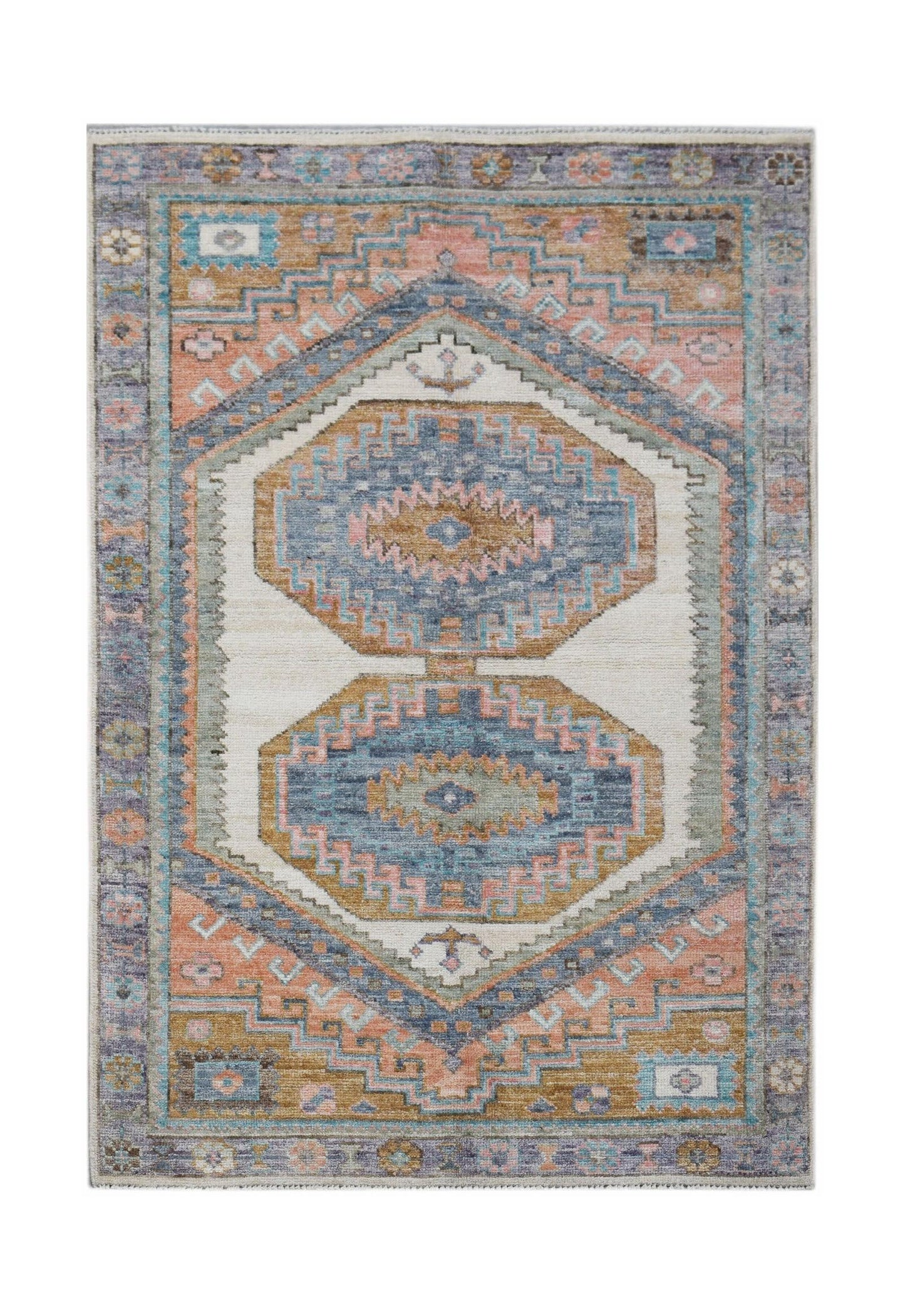 A handwoven transitional Oushak rug featuring geometric medallions in blue, pink, and gold tones.